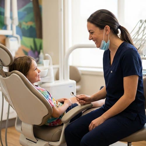 Dentist smiling with a young patient during a positive pediatric dental visit